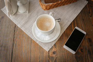 Top view of a smartphone and a Cup of coffee on a rustic wooden table.