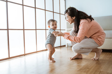 baby first step walking. mother help her baby to walk her first step at home