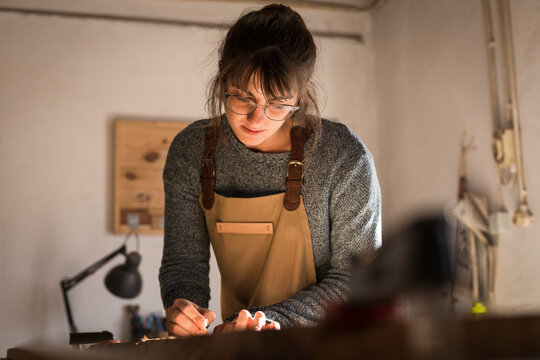 A young female carpenter drawing on a piece of timber while working with wood in a carpentry workshop. Young girl wood worker designing a new piece of furniture. Interior design concept