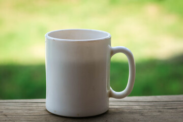 Obraz premium A white cup of tea on the railing of the Wooden terrace. Morning concept. Close-up.