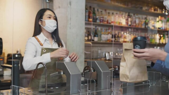Waitress send disposable paper bag and cup to customer in restaurant.