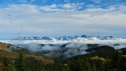 High Tatras above clouds with forested hills in the foreground, Tatras, Slovakia.