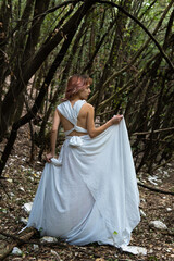 A woman in a white dress in the middle of the forest