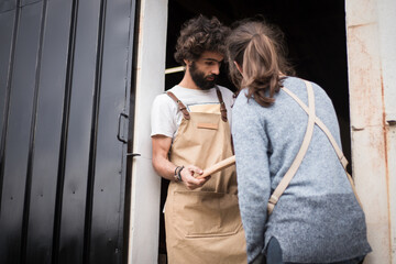 A young couple of carpenters working together in a small carpentry workshop designing a new home furniture piece crafting out of timber. Young entrepreneurs running their own business in Lisbon