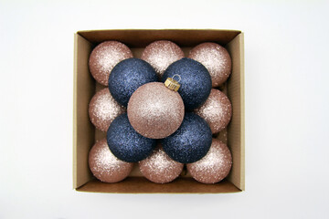 Christmas, new year, decorations. Christmas gold pink and blue trinkets, balloons in a cardboard box on a white background. Holiday the concept of preparing for Christmas. Flat bed, top view.