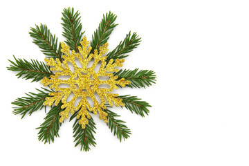 Green branches of a Christmas tree, a Golden snowflake on top on a white isolated background. Traditional Christmas decoration, decor. The view from the top. Flatly. Copy space.