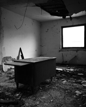 A messy room with an old desk and a dilapidated ceiling in an abandoned building