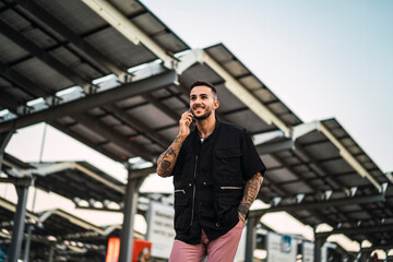 Fototapeta premium Chico joven tatuado en parking con smartphone