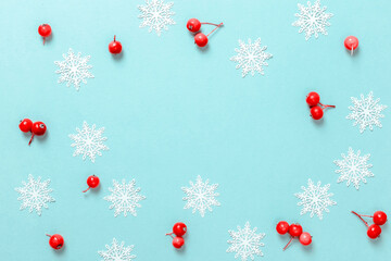 Christmas ornaments. White snowflakes, red berry in Christmas composition on pastel blue background for greeting card. Christmas, winter, new year concept.