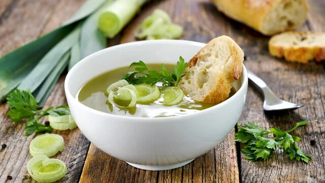 leek soup with bread on wood background