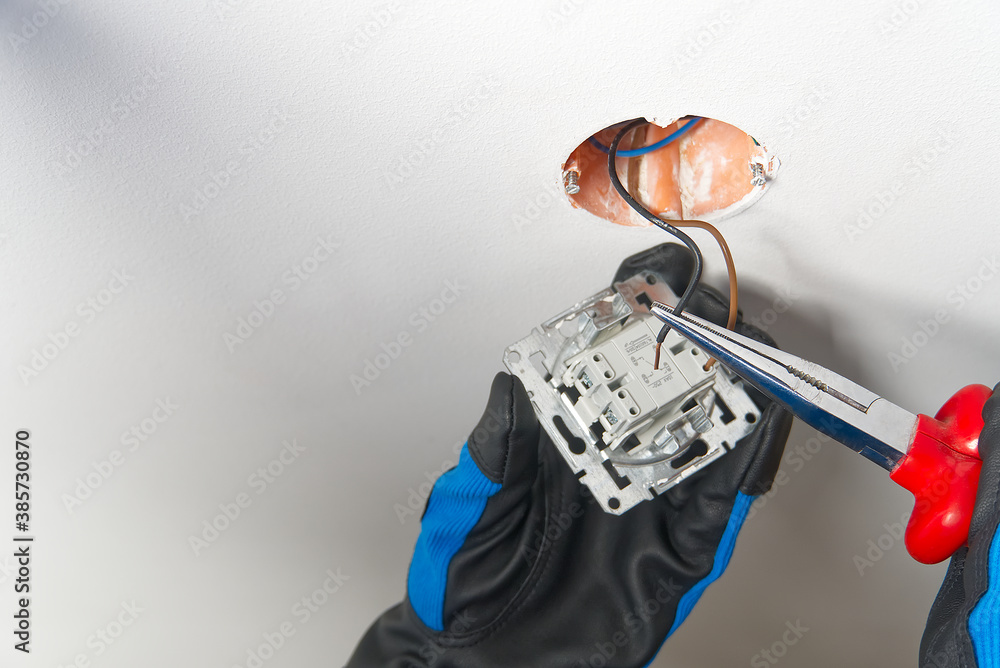 Poster electrician installing light switch on painted wall with screwdriver. man installing light switch af