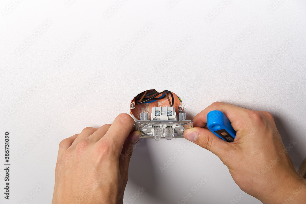 Poster electrician installing light switch on painted wall with screwdriver. man installing light switch af