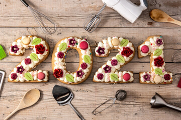 2021 cake decorated with flowers on wooden background.