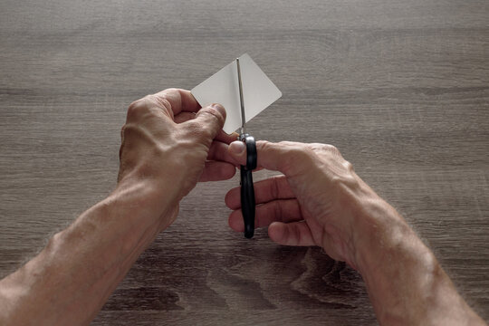 male hands with scissors cut the payment card. concept of liquidation, destruction of deactivation, decommissioning