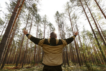 A guy walks through the woods on a sunny day