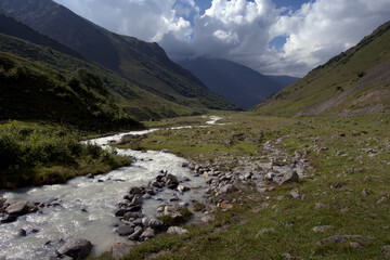 Fototapeta na wymiar Green alpine valley and river stream on a sunny summer day. Caucasus, Russia.