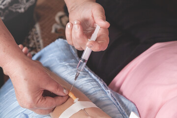 Doctor inputs liquid medicine by syringe to catheter in vein.