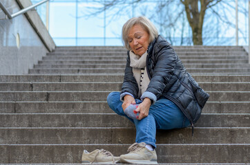 Helpless senior woman massaging her Foot