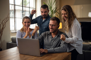 Obraz premium Authentic shot of young successful people are controlling emails on laptop exulting and celebrating an approved and promotion of new project in in creative agency office.