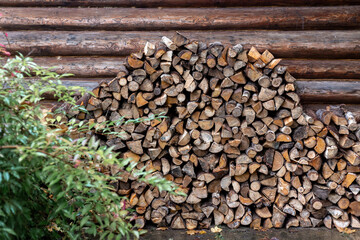 Lots of firewood stacked against a wooden wall