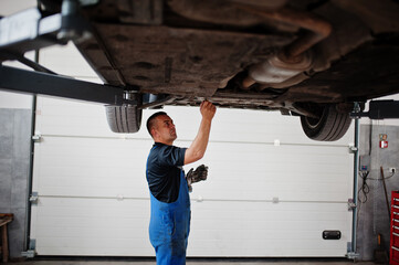 Obraz na płótnie Canvas Car repair and maintenance theme. Mechanic in uniform working in auto service.