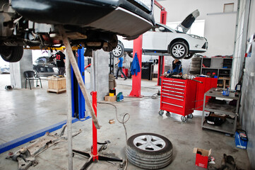 Cars lifting in maintenance at garage service station.