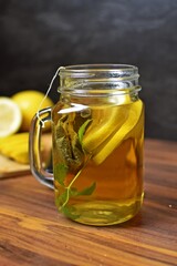 A glass is poured with hot water and a tea bag for peppermint tea hangs inside. Fresh peppermint tea is boiled up, suitable for the winter and flu season