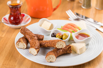 Turkish bagel served with tomatoes, cheese olives and honey on a white plate