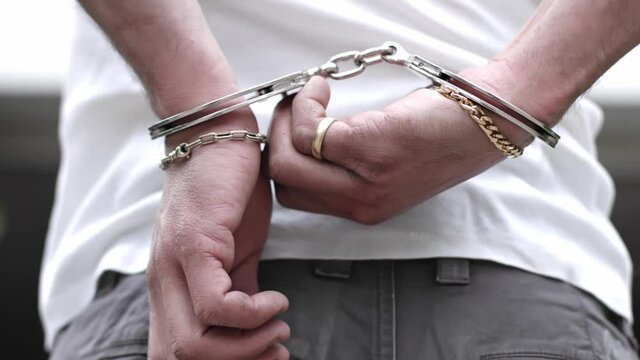 A criminal with hands behind opening handcuffs with a key.