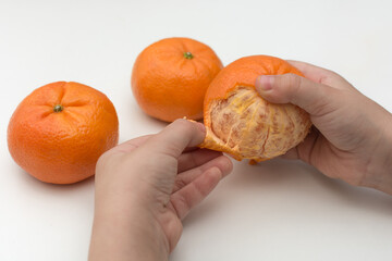 child's hands peel the tangerine, close-up photo, horizontal. The idea is a healthy, vitamin diet for children, develop fine motor skills and speech.