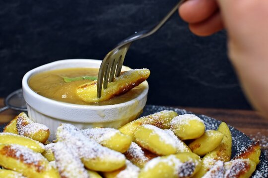 Delicious, fried Schupfnudeln from Germany lie covered with icing sugar next to a bowl of apple sauce. Delicious dessert as a sweet lunch in Germany