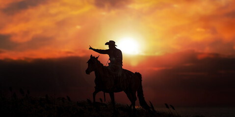 The silhouette of cowboy on horse with evening sunset landscape.