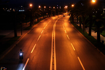 empty lighted street at night, trafic road with yellow lamp post lights 