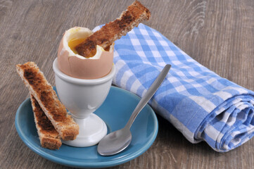 Oeuf à la coque dans son coquetier avec un morceau de pain toasté