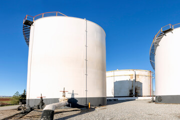 View of the cylindrical atmospheric fuel storage tanks with fixed roofs and internal floating roofs.