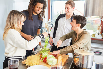 Laughing students prepare salad together in shared kitchen