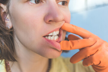Woman in gloves shows her crooked teeth.
