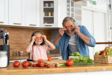Cute little girl and her handsome dad are having fun while cooking in kitchen at home
