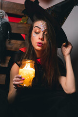 A girl in a witch costume holds her hat in her hand