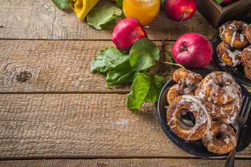Autumn sweet dessert recipe. Homemade apple cider donuts. Baked donuts with sugar, cinnamon glaze and white sugar topping drizzle, on wooden background with fresh apples