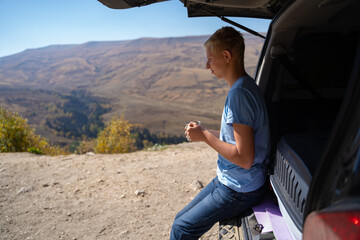 young man is resting in nature with an off-road vehicle