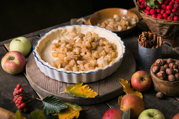 Baking background with raw traditional classic apple pie, bake  ingredients and utensils. Homemade  cake surrounded by fresh fruits
