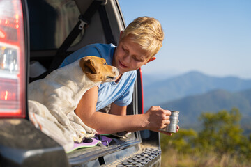 young man is resting in nature with an off-road vehicle and a jack russell terrier