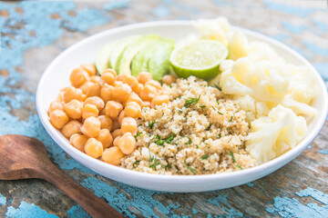 A bowl of healthy vegan and vegetarian lunch or dinner. Salad of fried chickpeas, quinoa, avocado, cauliflower on a light background.Top view, flat lay