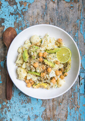 A bowl of healthy vegan and vegetarian lunch or dinner. Salad of fried chickpeas, quinoa, avocado, cauliflower on a light background.Top view, flat lay