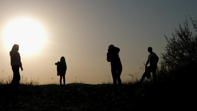 family of three photographed at sunset by the sea in silhouette