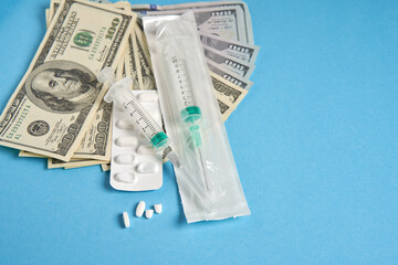 pills empty blisters for drugs individual syringe and money lie on a blue background