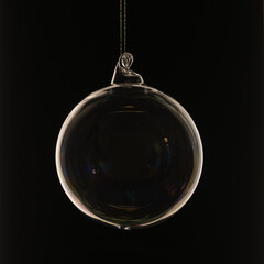 Gläserne Christbaumkugel vor schwarzem Hintergrund mit streiflicht