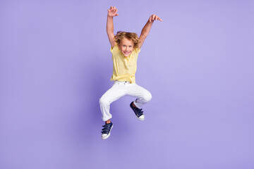 Fototapeta na wymiar Full length photo of spooky small boy jump attack with hands claws wear t-shirt trousers isolated on purple color background