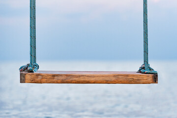 Wooden swing with ropes overlooking the sea. Swing on seashore. Close up